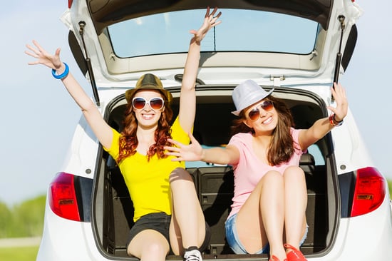 Young happy young woman sitting in car trunk outdoor